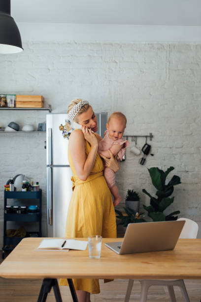 istock Working Mom Holding Her Baby While Talking on the Mobile Phone at Home 1367213680