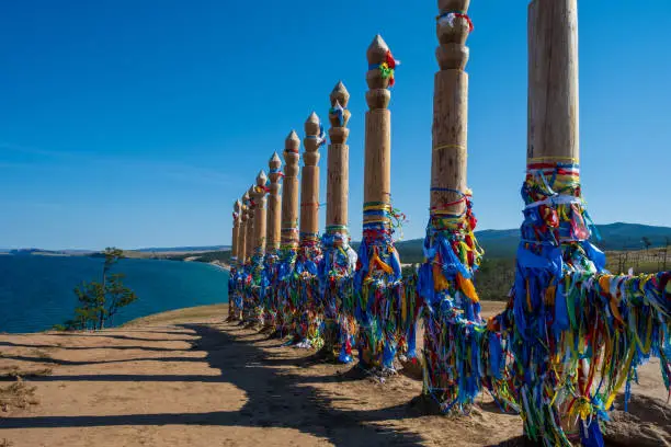 Colorful ribbons on the wooden pillars in sacred buryat place on cape Burkhan in Khuzhir village in Olkhon island in sunny autumn day