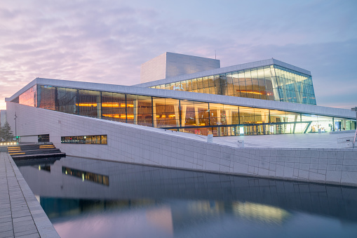 Oslo, Norway – April 14, 2022: Oslo's Bjorvika (Inner Harbor) during sunrise with the calm water reflecting the famous Oslo Opera House.