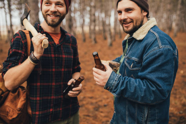 istock Two millennial man hiking and drinking beer in a forest, laughing and having fun. 1367215538