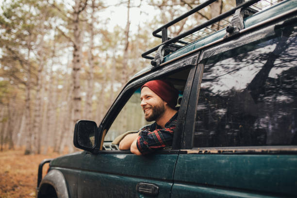 istock Millennial man travelling off-road by car in a forest. Wanderlust concept. 1367215568