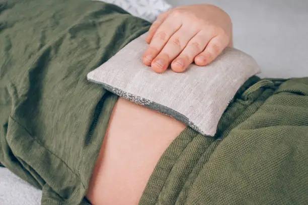 Boy using cherry pits heating pad. Cherry stone thermal pillows, cherry pit filled pillow. Alternative medicine and therapy, pit sack for spa massage, chiropractic care. Selective focus