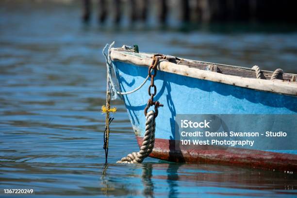 Front Of Small Blue Row Boat With Anchor Rope Hanging Off The Front And Disapearing In The Calm Watter Stock Photo - Download Image Now