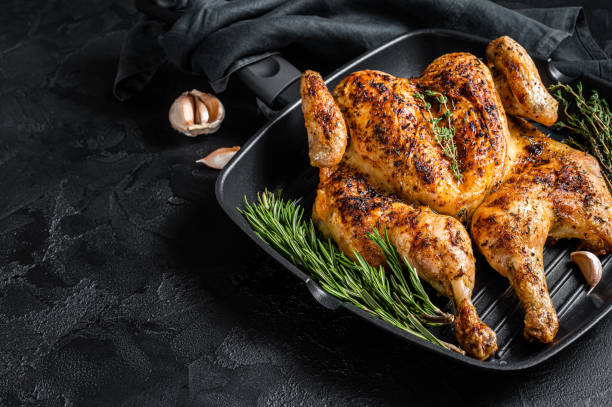 istock BBQ spatchcocked barbecue whole chicken on grill pan. Black background. Top view. Copy space 1367221570