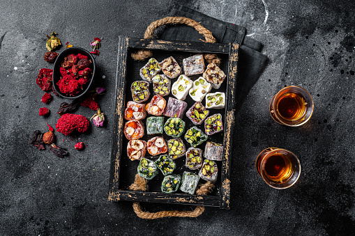 Turkish Delight Lukum, Oriental sweets with nuts and black tea. Black background. Top view.