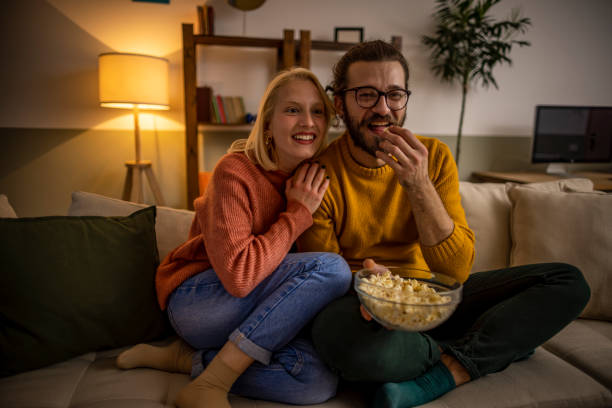 coppia che guarda la tv e mangia popcorn - family television watching watching tv foto e immagini stock