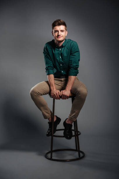istock Smiling young man sitting isolated over grey background 1367223037