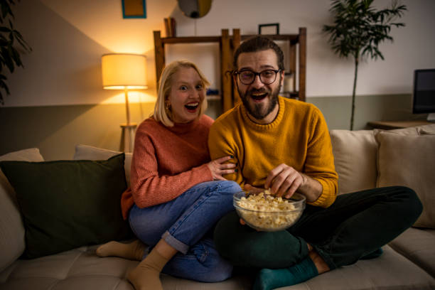 istock Couple watching TV and eating popcorn 1367224452