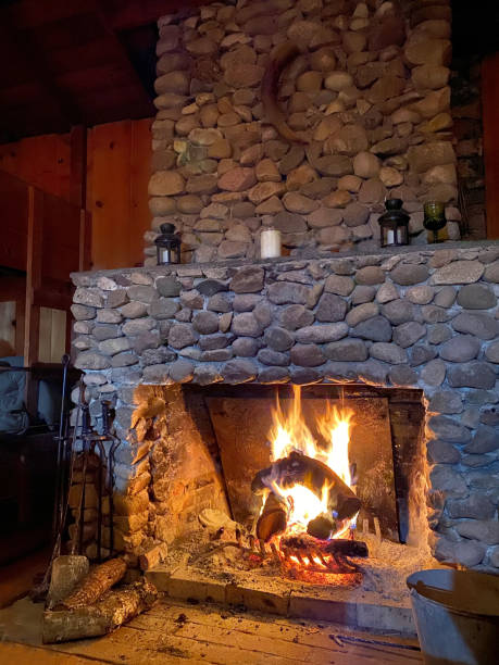 Vintage rock fire place with open hearth and warm fire stock photo