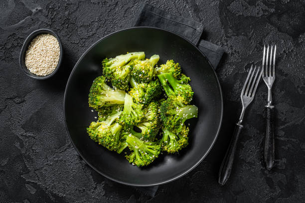 istock Boiled broccoli with spices in a plate. Black background. Top view 1367227948