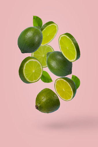 istock Creative idea with whole and sliced lime flying in the air isolated on pastel pink background. 1367229105