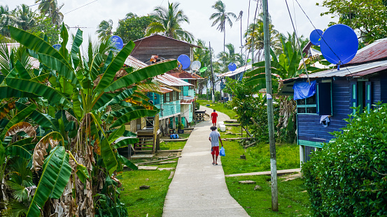 Bocas del Toro, Panama-March 2018: Tropical view of a local village located on the famous Panamanian archipelago with traditional wooden houses surrounded with green lush jungle vegetation.