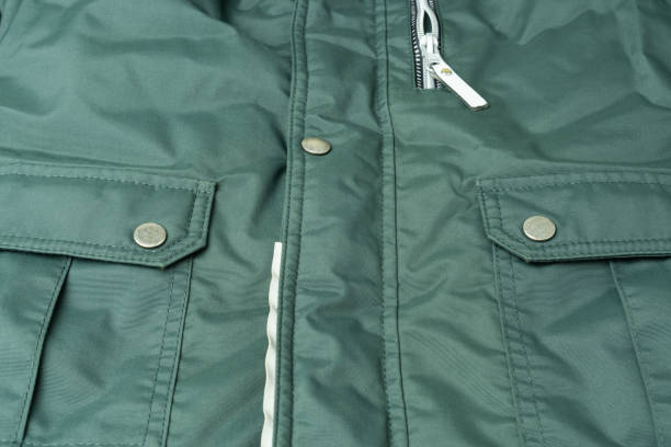 fragment einer grünen jacke aus wasserdichtem stoff mit hochwertigen nähten, taschen, metallknöpfen und reißverschluss. - fashion industry textile man made material green stock-fotos und bilder