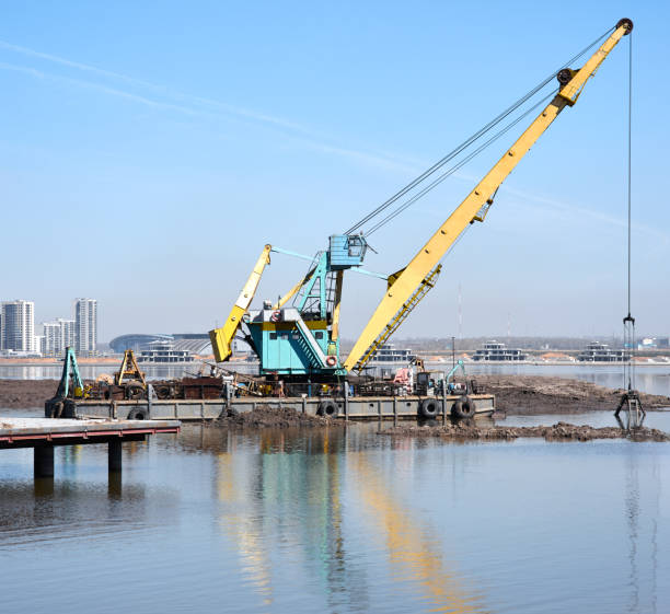 funktionierender baggerkran in küstennähe - industrial ship earth mover barge yellow stock-fotos und bilder