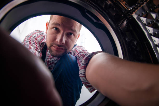 istock UNIFORM GUY REPAIRING WASHING MACHINE IN BATHROOM 1367239285