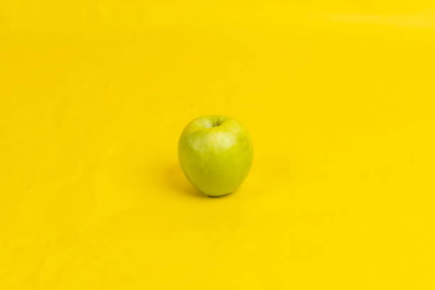istock a green apple on a yellow background 1367240037