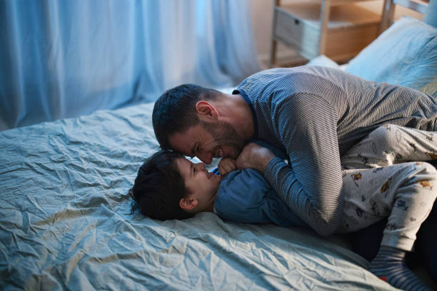 istock Father and son playing and cuddling in bed before bedtime 1367240050