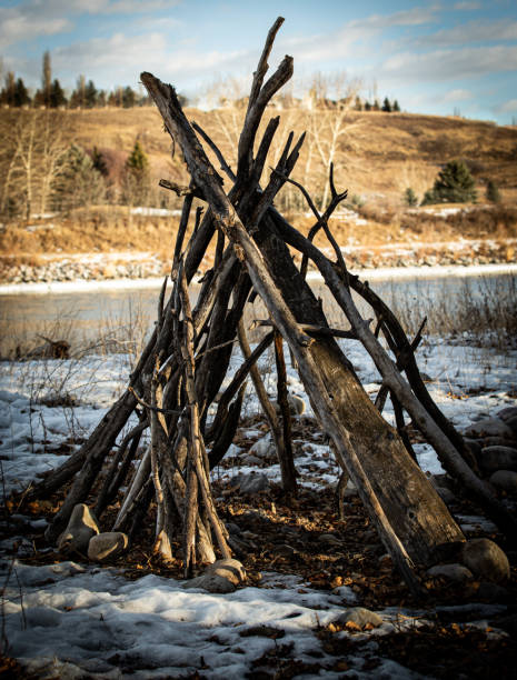 teepee fatto di alberi vicino al fiume. - north american tribal culture teepee winter canada foto e immagini stock