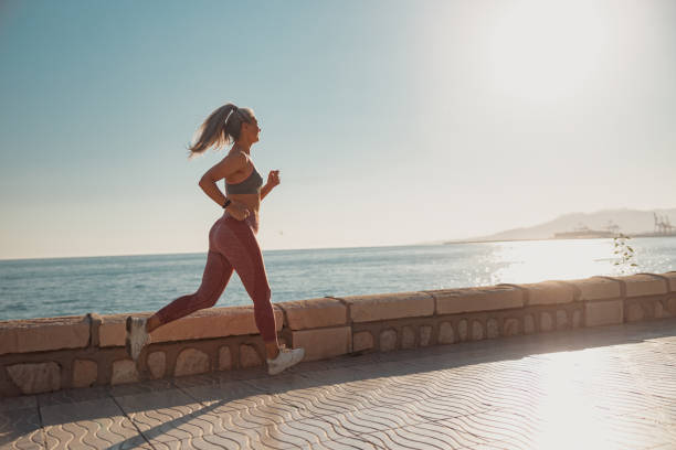 istock Sporty lady actively jogging by the waterfront 1367240507