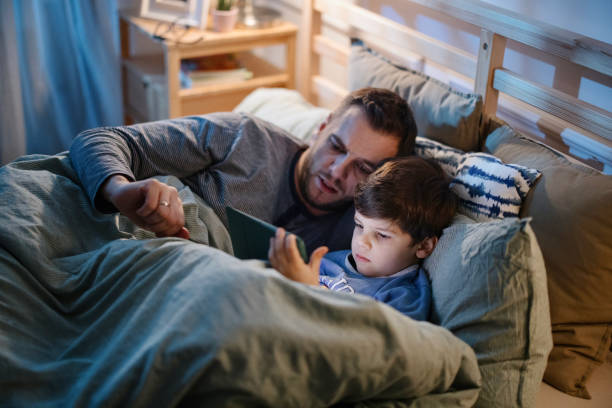 istock Father and son reading bedtime story from digital tablet late at night 1367240633