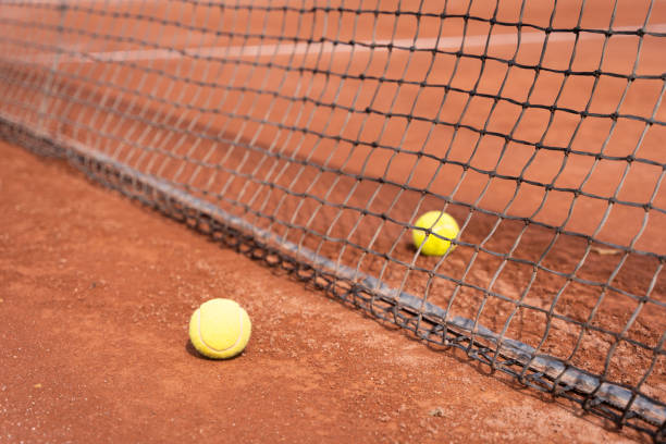 istock Two tennis balls on clay court 1367241432