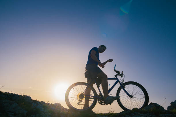 istock Strong fit male mountain biker performing stunts on rocky terrain on a sunset while wearing a blue shirt and riding a blue bike 1367242373