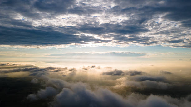 istock Aerial view of a cloudy sunset while flying above the clouds. 1367243343