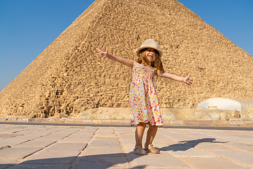 Cute little girl dancing in front of the Cheops pyramid on the Giza plateau
