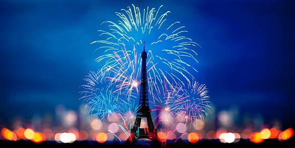 Fireworks over Eifel tower in Paris, France with blurred night skyline