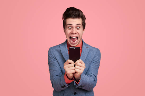 istock Excited young businessman with smartphone screaming 1367247139