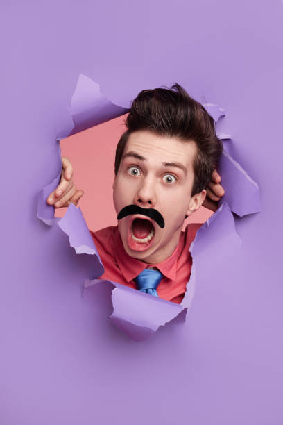 istock Funny detective peeking from hole in paper 1367247155