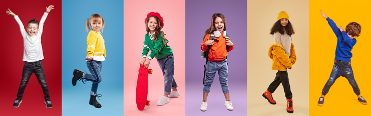 Set of playful multiethnic kids in stylish casual clothes having fun while standing against bright background in studio