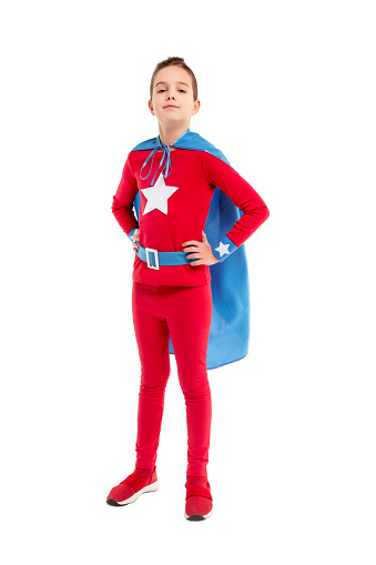 Fearless confident child in superhero costume standing with hands on waist on white background and looking at camera