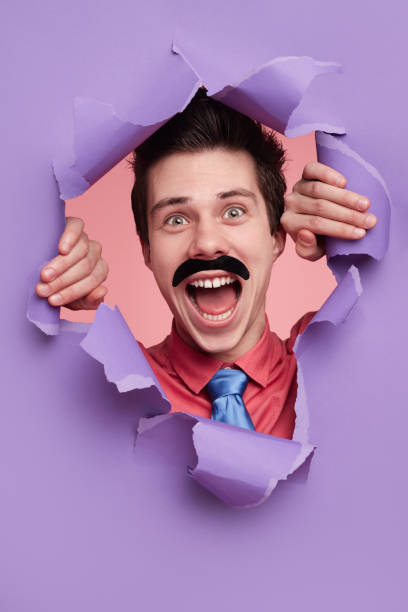 istock Excited man looking through hole in torn paper 1367247284