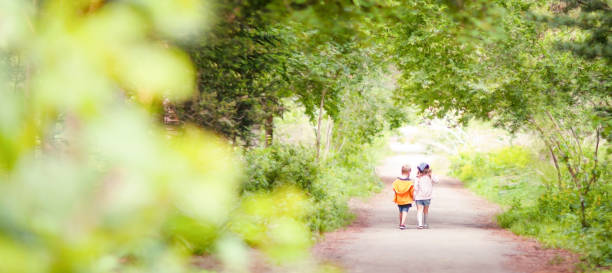 blurred background where a boy and a girl are walking on a sunny path