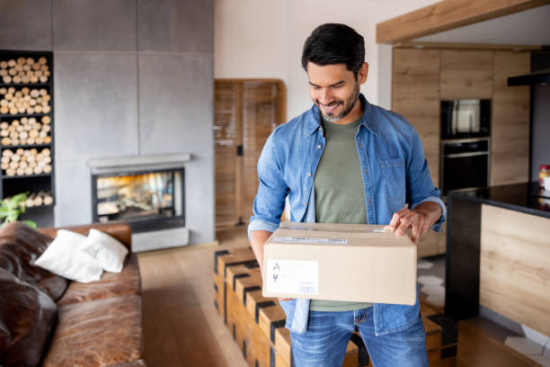 uomo felice che riceve un pacco a casa - package foto e immagini stock