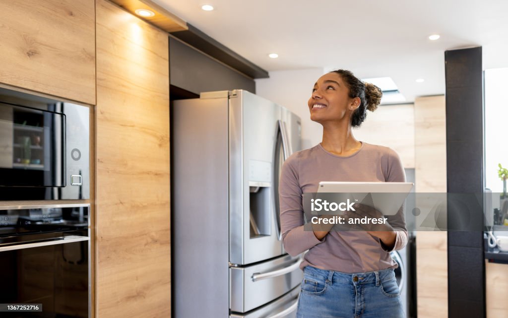 Woman controlling the lights of her smart house using an automated system Happy woman controlling the lights of her smart house using an automated system from a tablet computer Home Automation Stock Photo