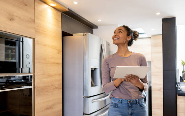 Woman controlling the lights of her smart house using an automated system Happy woman controlling the lights of her smart house using an automated system from a tablet computer home automation stock pictures, royalty-free photos & images