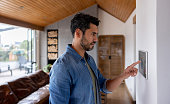 istock Man controlling the ambiance of his house using a home automated system 1367252746