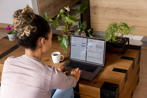 woman at home checking her bank statements online - rekening stockfoto's en -beelden