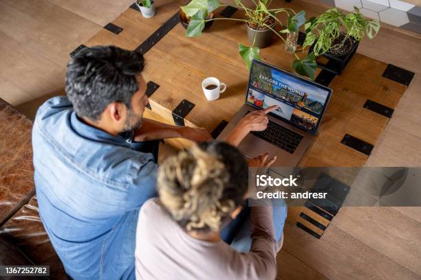 Happy Couple At Home Booking A Trip Online Stock Photo - Download Image Now - Planning, Vacations, Travel