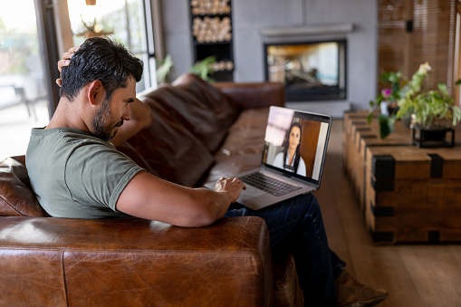 Latin American sick man at home talking to a doctor via video call - telemedicine concepts