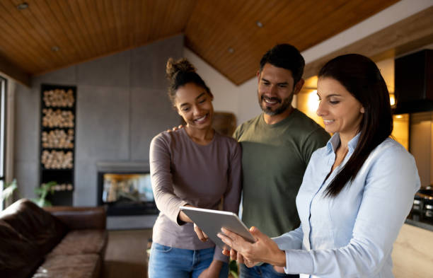 Real estate agent showing a house to a couple Real estate agent showing a house to a couple and teaching then to use the automated system on a tablet estate agent stock pictures, royalty-free photos & images