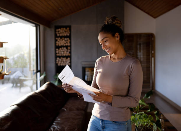 woman at home checking her mail - opening mail letter envelope imagens e fotografias de stock