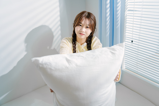 Asian women having fun with pillows in the morning