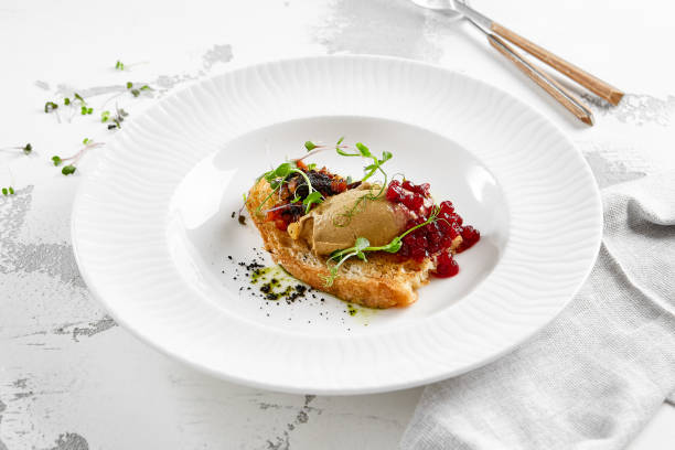 istock Chicken liver pate on crispy bread with red currant jam and micro green. Bruschetta with chicken pate in white plate. Delicious appetizer - foie gras on toast. Liver pate with jam in rustic style. 1367256336