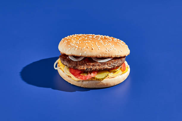 istock Beef burger blue background with hard shadow. American junk food minimal style. Hamburger trendy style.  Simple burger colour background. 1367256371