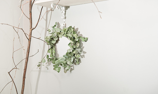 eucaliptus branch wreath hanging on a wall, spring decor in a rustic style home. seasonal decoration for spring holidays. copy space