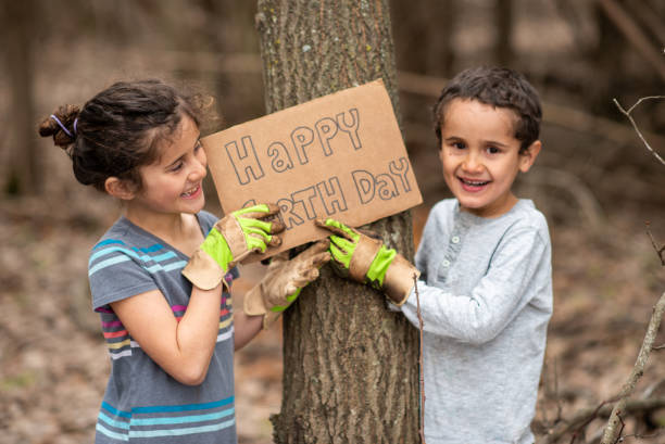 Happy Earth Day A sweet little girl of Hawaiian decent, holds up a "Happy Earth Day" sign with her brother as  they proudly cleans up the forest around them.  They are dressed casually and wearing gardening gloves as they smile happily. earthday stock pictures, royalty-free photos & images