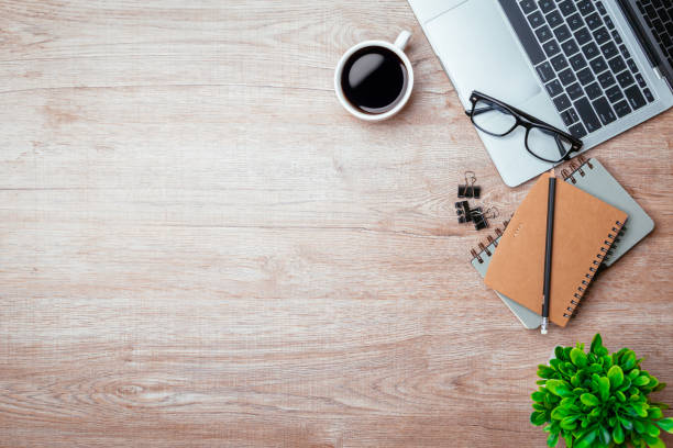 istock Work from home. desk office with laptop, blank notepad, coffee cup and pen on wood table. Flat lay top view copy spce. 1367265108